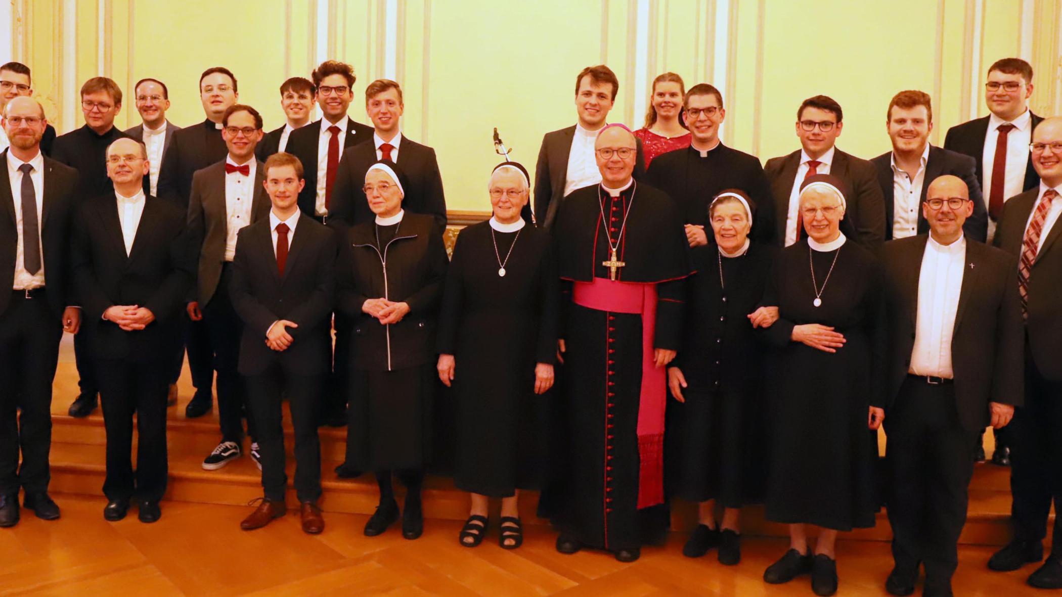 Zu sehen ist ein Gruppenfoto: Auf der Bühne der Promotionsaula steht Bischof Dr. Stephan Ackermann, gemeinsam mit den Schwestern, Regens Oliver Laufer-Schmitt, den Seminaristen und Felixianern.