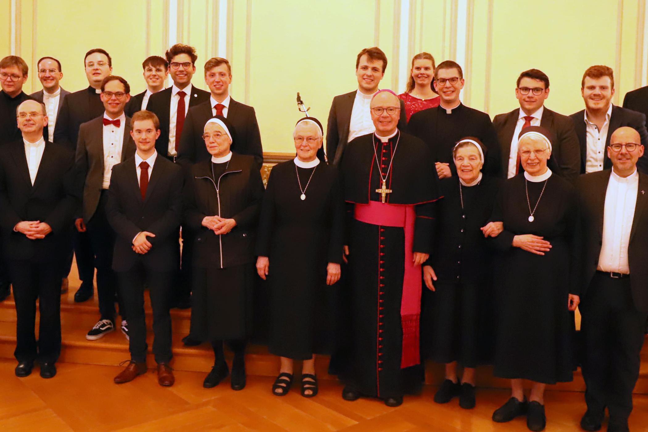 Zu sehen ist ein Gruppenfoto: Auf der Bühne der Promotionsaula steht Bischof Dr. Stephan Ackermann, gemeinsam mit den Schwestern, Regens Oliver Laufer-Schmitt, den Seminaristen und Felixianern.