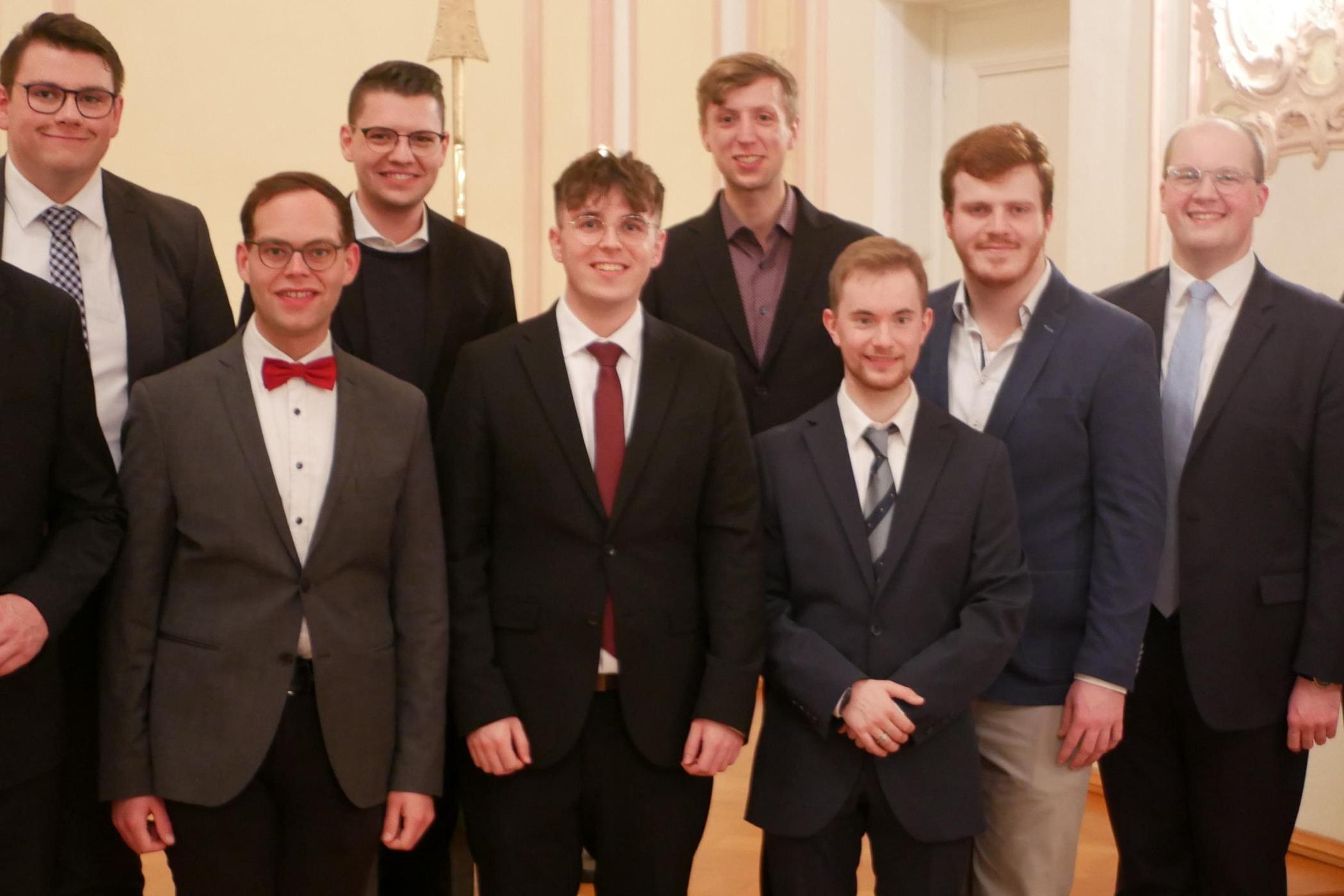 Zu sehen ist ein Gruppenfoto: Auf der Bühne der Promotionsaula stehen die Seminaristen in zwei Reihen, mit Regens Tim Sturm (links) und Spiritual Jan Lehmann (rechts). Alle tragen einen Anzug und sind festlich gekleidet.