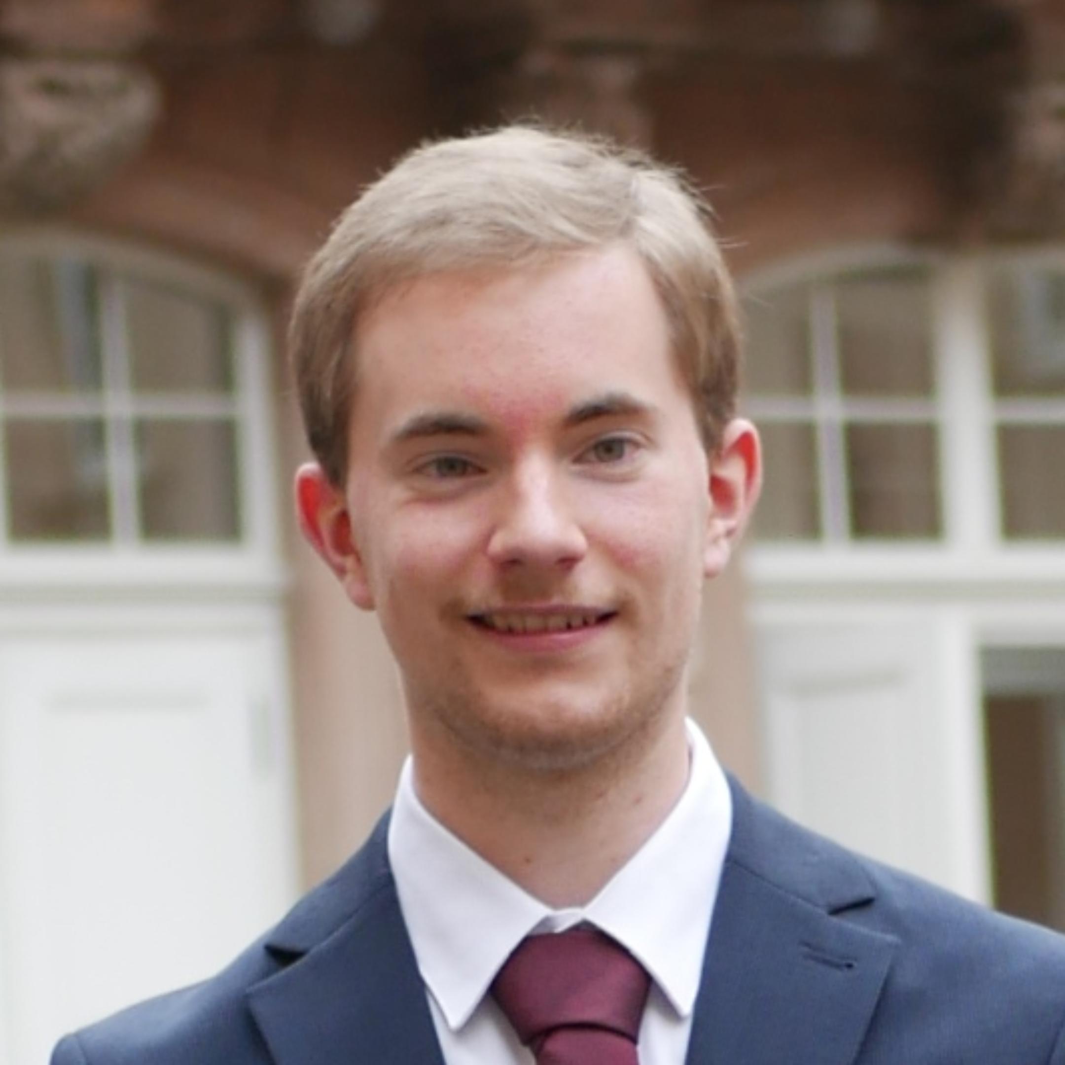 Portraitfoto von Lukas Wolber, im Hintergrund befindet sich der Aulaflügel.
