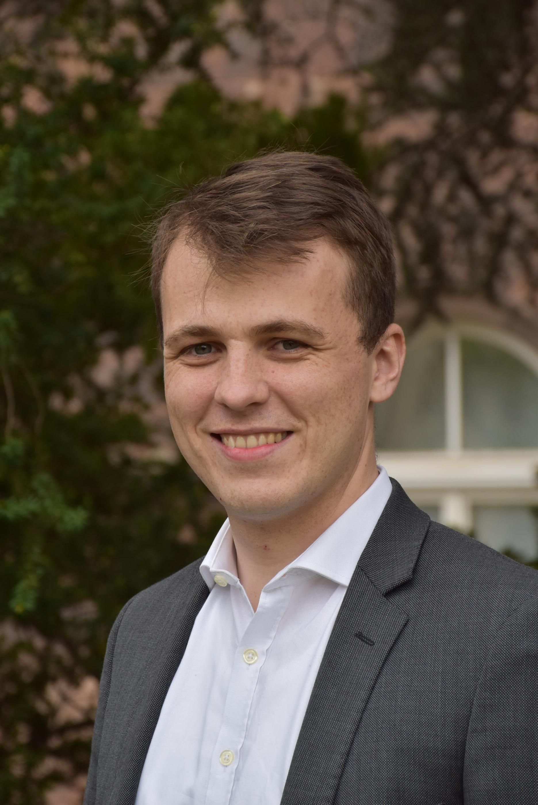 Portraitfoto von Mathieu Valet, im Hintergrund befindet sich das Felizianum.