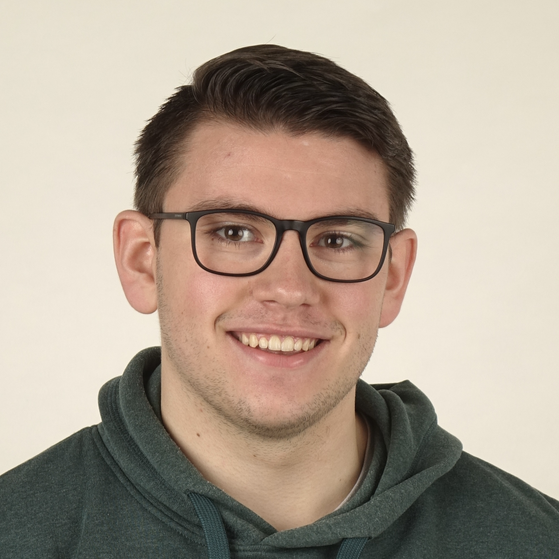 Portraitfoto von Noah Jakob Bach vor einem beigen Hintergrund.