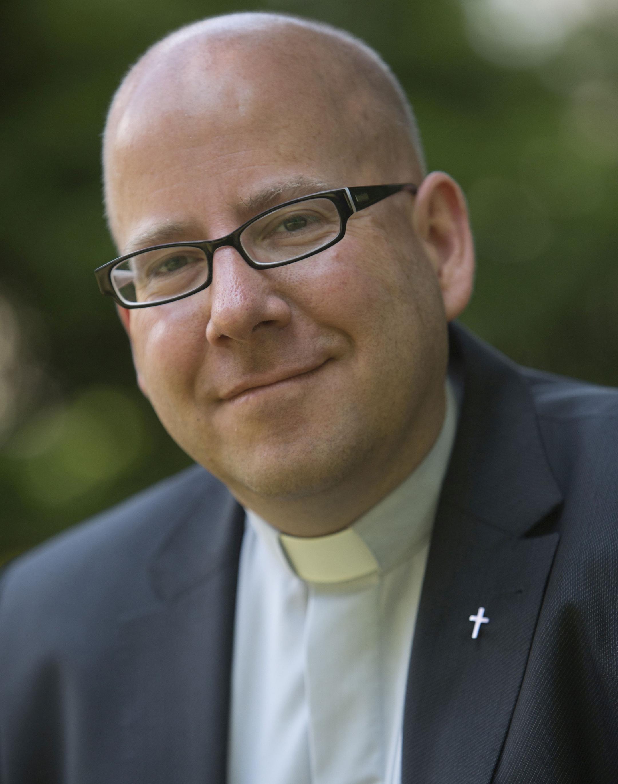 Portraitfoto von Oliver Laufer-Schmitt vor einem grünen, unscharfen Hintergrund.