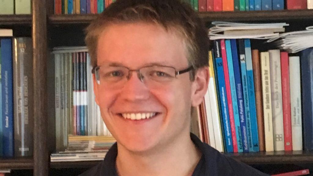 Portraitfoto von Pascal Klose. Im Hintergrund ein Bücherregal.