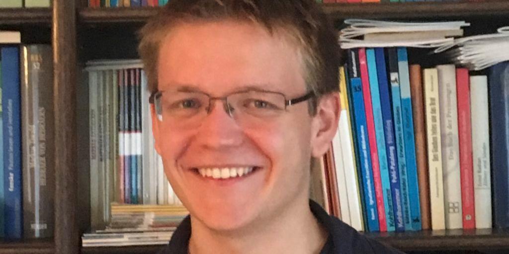 Portraitfoto von Pascal Klose. Im Hintergrund ein Bücherregal.