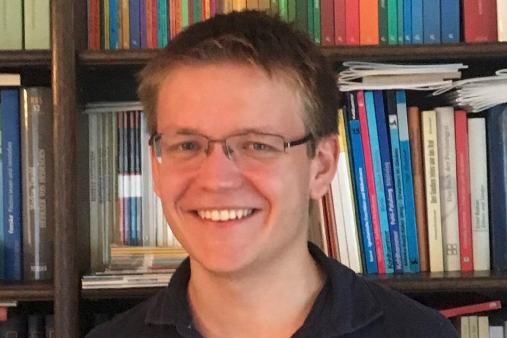 Portraitfoto von Pascal Klose. Im Hintergrund ein Bücherregal.