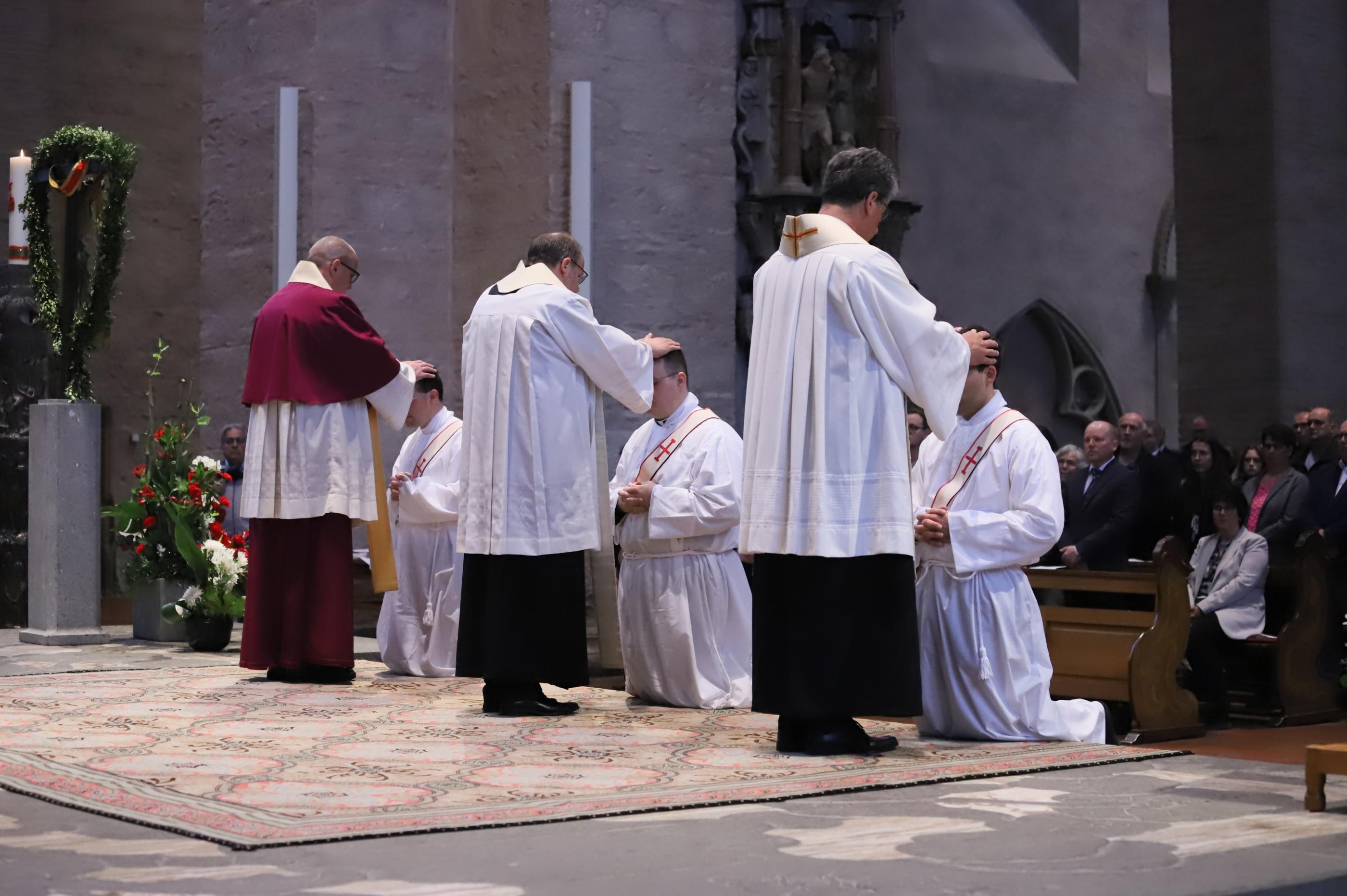 Priester legen den Neugeweihten die Hand auf.